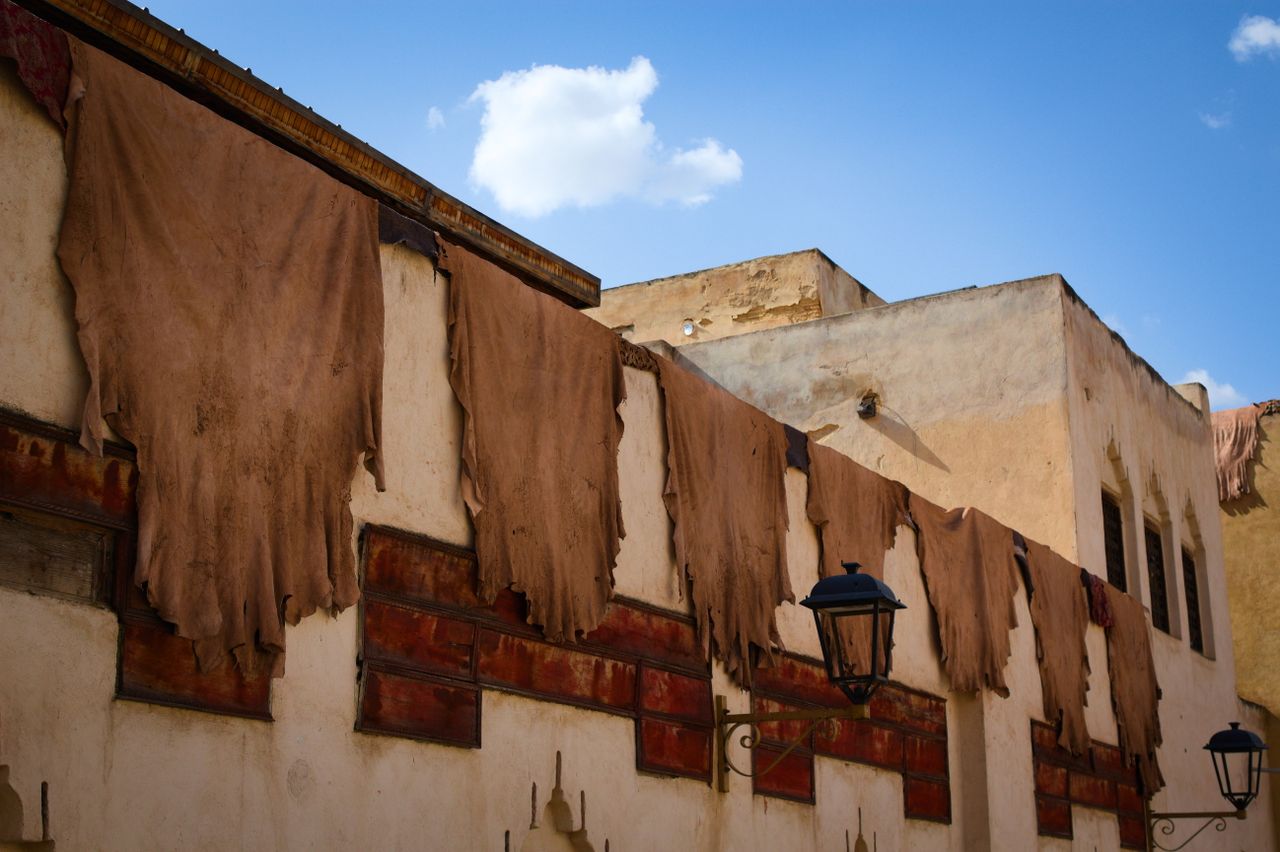Mastering the First Impression: Your intriguing post title goes here Old tannery in Fes, Morocco with leather hides drying on building exterior under blue sky.