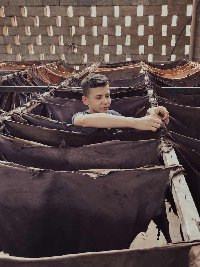 The Art of Drawing Readers In: Your attractive post title goes here Teenager works in a tannery, arranging leather hides on drying racks indoors.