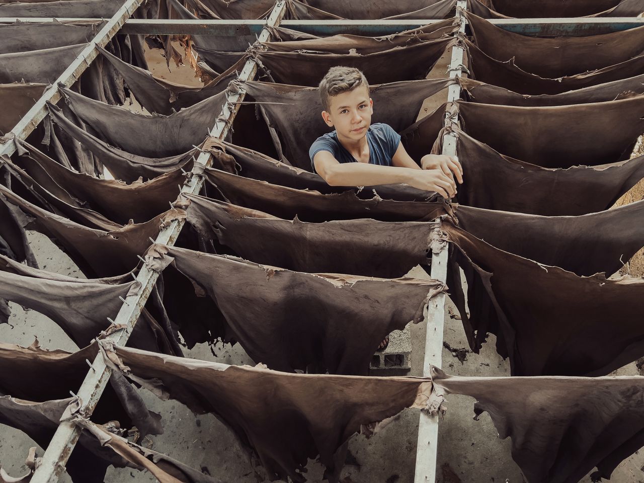 Crafting Captivating Headlines: Your awesome post title goes here A teenager stands among drying leather racks in a tannery, showcasing traditional leather production.